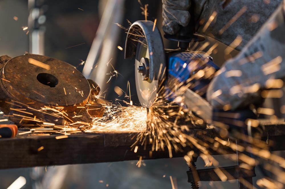 Worker cutting metal with grinder. Sparks while grinding iron